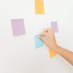 a person posting sticky notes on a white wall