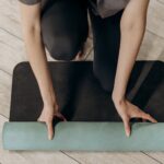 woman in black leggings unrolling a yoga mat