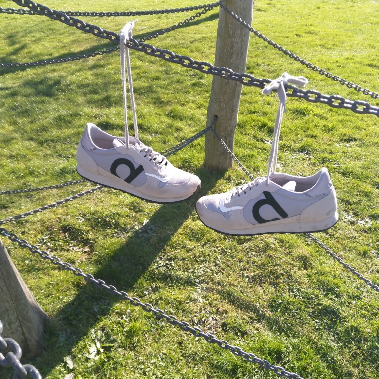 Wie het schoentje past: sneakers, opgehangen aan hun veters. 