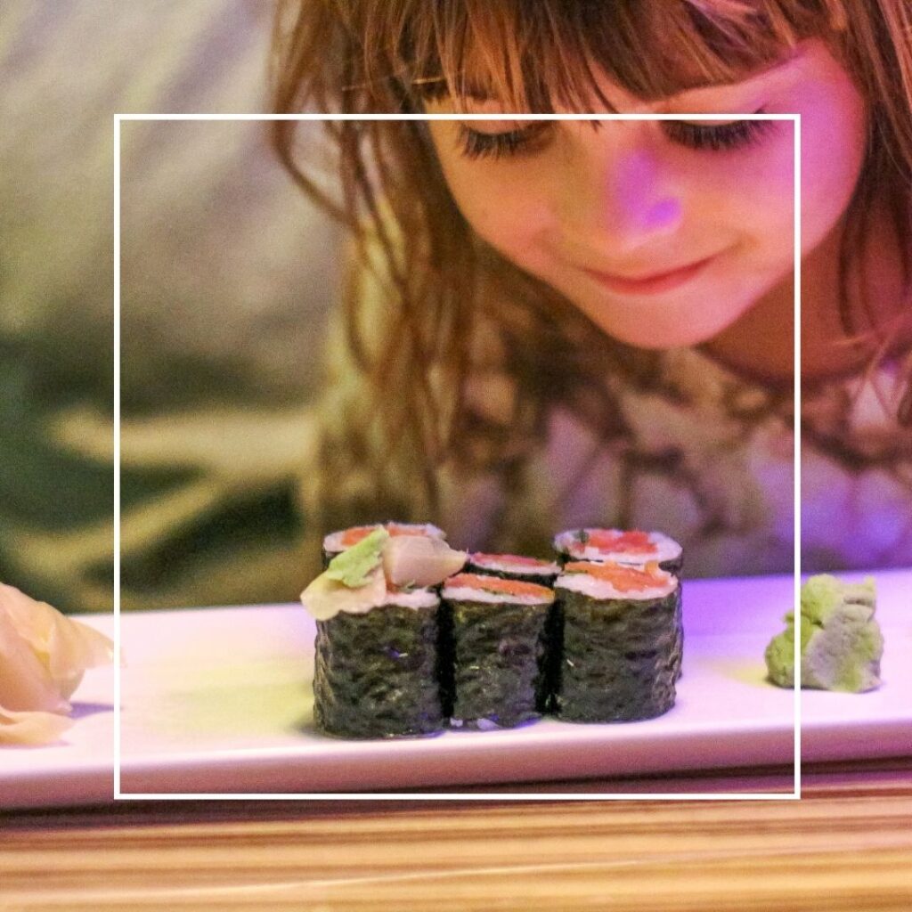 Een meisje bewondert rolletjes sushi