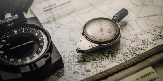 shallow focus photography of black and silver compasses on top of map